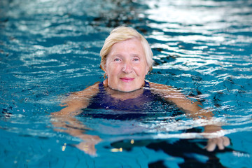 Healthy senior woman swimming in the pool. Happy pensioner enjoying sportive lifestyle. Active retirement concept.