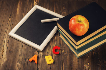 Back to school concept. Blackboard with a chalk, old books, apple and plastic letters. Vintage...