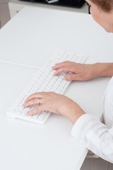 パソコンのキーボードを操作する高齢者女性の手