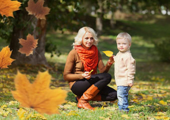 Happy mom and child playing together in warm autumn day, flying