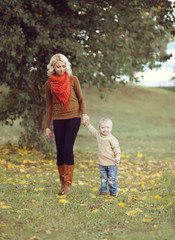 Happy mother and child walking together in the autumn park