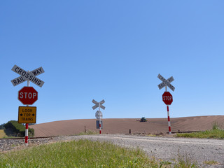 Naklejka premium railway crossing signs with tractor in background. New Zealand. 