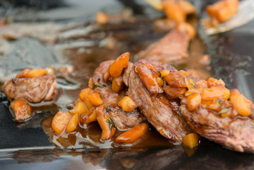 dish of pork with sauce on black plate