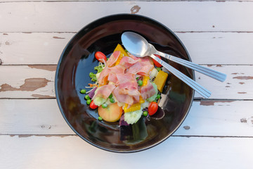 Salad of ham, bacon, tomatoes, cucumbers, olives on a plate.Top