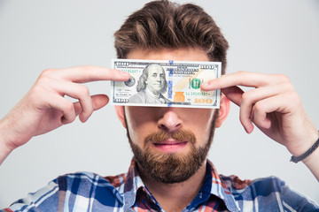 Man covering his eyes with bill of USA dollar