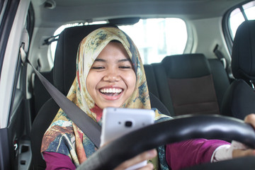 muslim woman holding handphone while driving