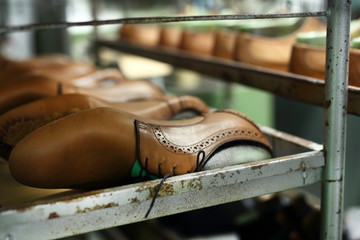 Regał w pracowni szewskiej z ustawionymi parami eleganckich męskich butów - obrazy, fototapety, plakaty