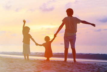 father with kids silhouettes having fun at sunset