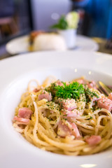 Spaghetti carbonara (with ham) on white plate