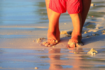 Mother and baby feet walking on beach