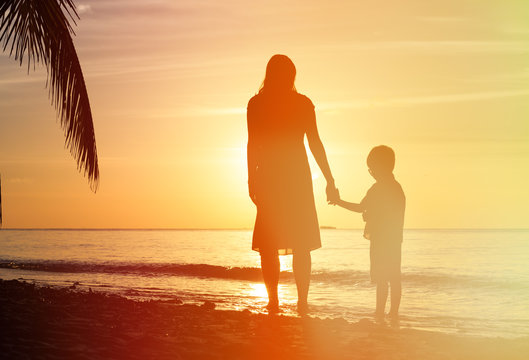 Silhouettes Of Mother And Son Holding Hands At Sunset