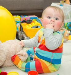 Funny infant in bright bode sitting on a floor with toys - 88470196