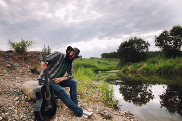 guitarist in a cowboy hat on the nature