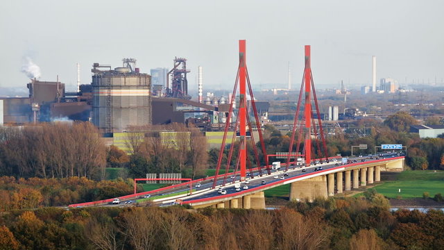 View to the A42 motorway bridge of Rhine River in Duisburg, Germany with a gasometer and steel industry in the background.