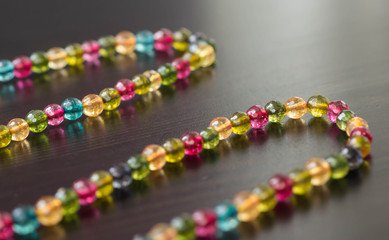 Necklace from glass beads of different colors on a dark surface close up