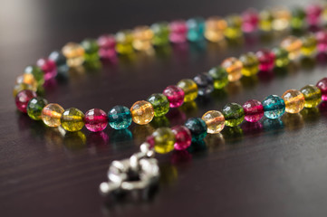 Necklace from glass beads of different colors on a dark surface close up