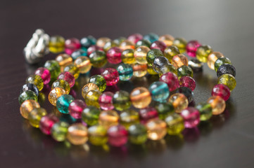 Necklace from glass beads of different colors on a dark surface close up