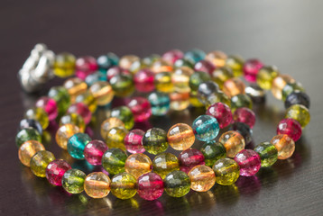 Necklace from glass beads of different colors on a dark surface close up