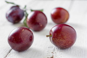 ripe plums/ five large ripe plums on white boards closeup