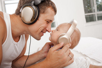 young father with his nine months old som on the bed at home