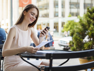 A smiling young woman looks at her smart phone.