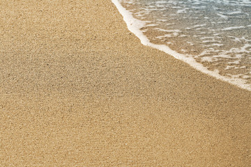 Sand on the beach. Summer waves on the sandy beach. Sea water foam. Fine yellow sand.