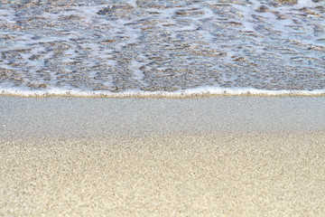 Sand on the beach. Summer waves on the sandy beach. Sea water foam. Fine yellow sand.