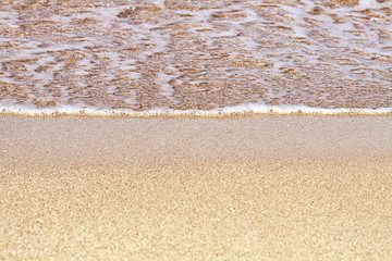 Sand on the beach. Summer waves on the sandy beach. Sea water foam. Fine yellow sand.
