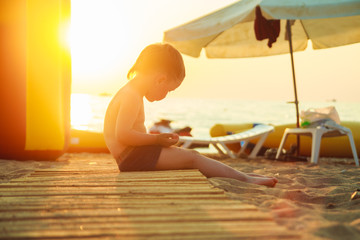 Obraz na płótnie Canvas boy sitting on the beach at sunset 