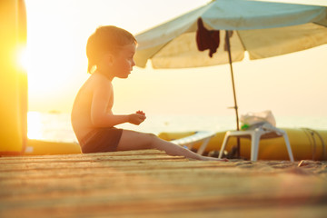 Obraz na płótnie Canvas boy sitting on the beach at sunset 