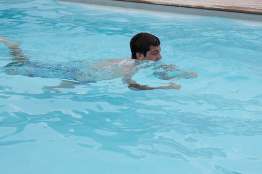 A Teenager swims in a pool on summertime
