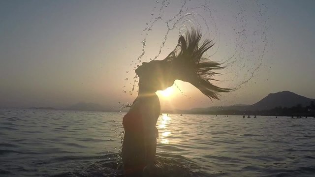 CHICA SALIENDO DEL MAR SALTANDO Y SALPICANDO CON SU PELO: grabado a c&aacute;mara lenta a 120fps camara en mano