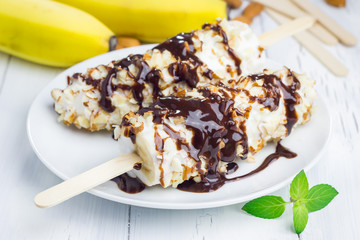 Frozen banana covered with yogurt, almonds and chocolate syrup