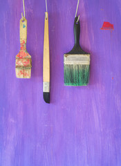 various paintbrushes on purple background, grungy style, free copy space
