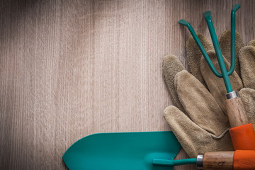 Leather gardening gloves hand spade and rake on wooden board agr
