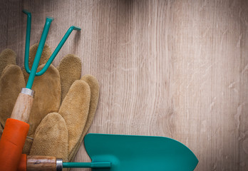 Leather gardening gloves metal hand spade and rake on wood board