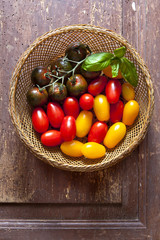 multicolor red and yellow cherry tomatoes in a wooden basket wit