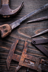 Rusted vintage measuring calipers hand saw and claw hammer on vi