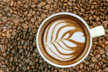 Coffee bean background with cup of fresh hot espresso coffee art