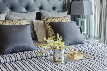 tray of book with vase of  plant on bed in luxury black bedroom