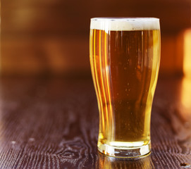 full tall glass of beer on wooden background
