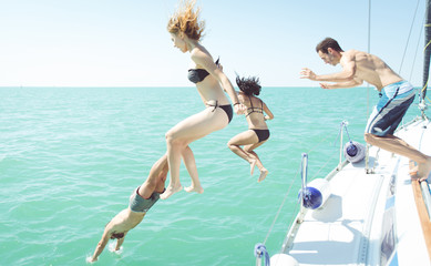 group of friends diving in the water during a boat excursion