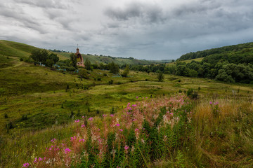 Fototapeta na wymiar destroyed orthodox church and old cemetery in cloudy morning, in the foreground the blossoming flowers