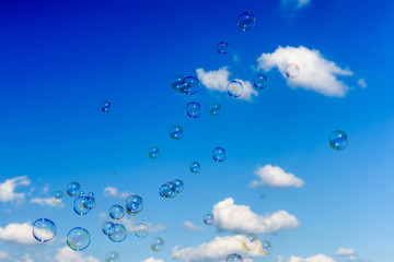 A bunch of soap bubbles flying up into the dark blue sky