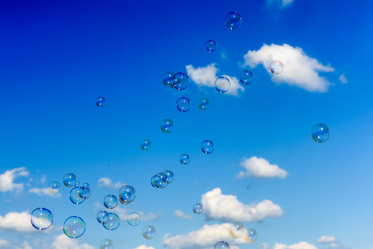 A bunch of soap bubbles flying up into the dark blue sky