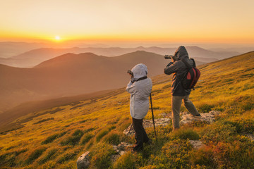 Photographers takes a sunset in the mountains - obrazy, fototapety, plakaty