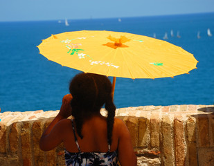 Mädchen mit Sonnenschirm schaut auf das Meer
