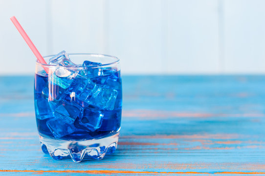 Blue alcohol or alcohol-free cocktail with straw and ice cubes