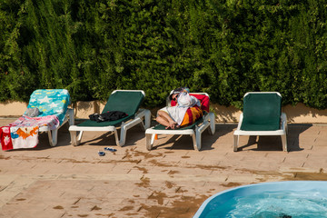 Un homme se cache sous sa serviette, allong&eacute; sur un transat au bord d'une piscine
