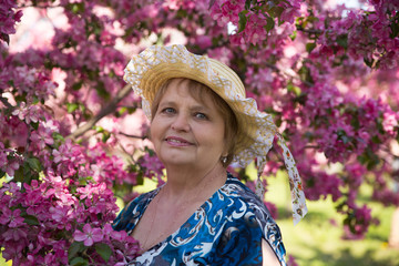 adult woman in hat under pink flowers trees